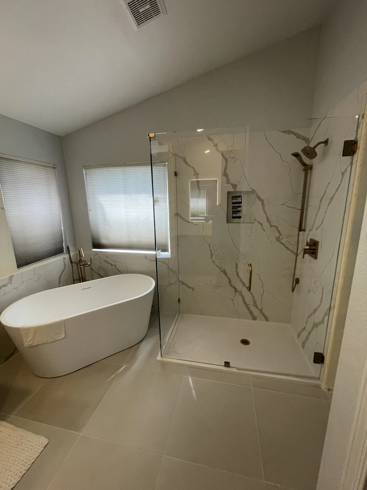 Finished master bathroom with a freestanding tub, frameless glass shower, and marble-look quartz walls by the Orange Cactus Remodeling team in Chandler, AZ