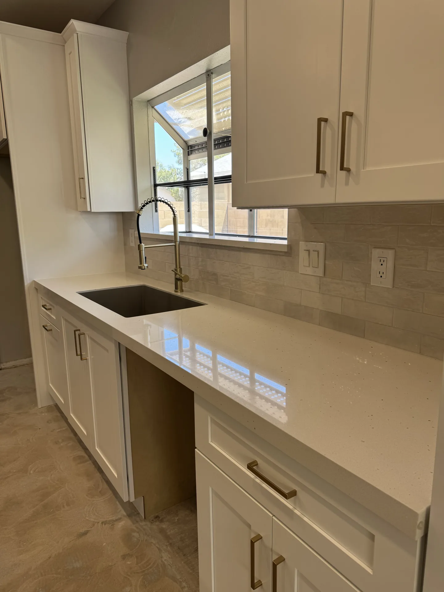 Transitional kitchen with white shaker cabinetry, quartz counters, brass hardware, and a gold faucet