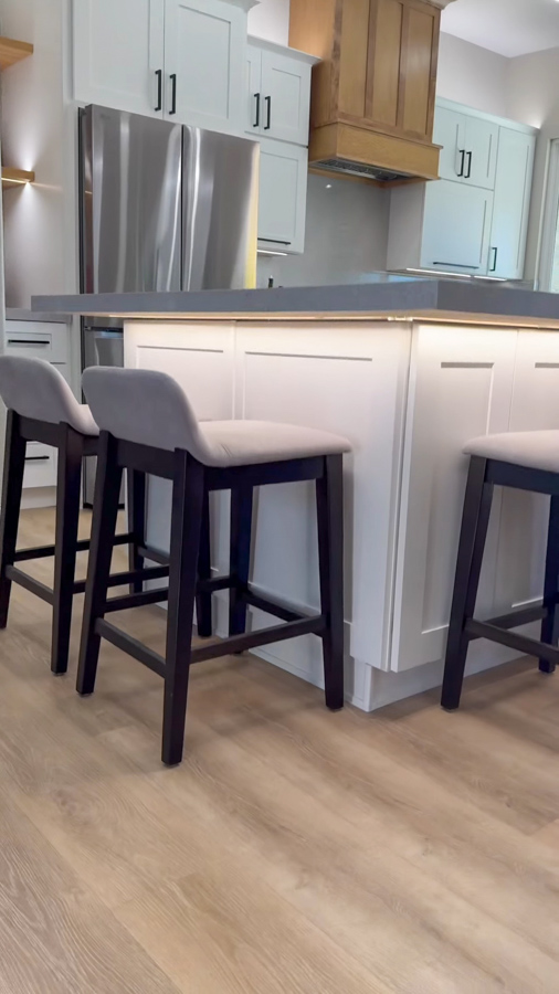 Kitchen island with white cabinetry, a dark counter, and barstools from a kitchen remodel by Orange Cactus Remodeling, serving Sun Lakes, AZ
