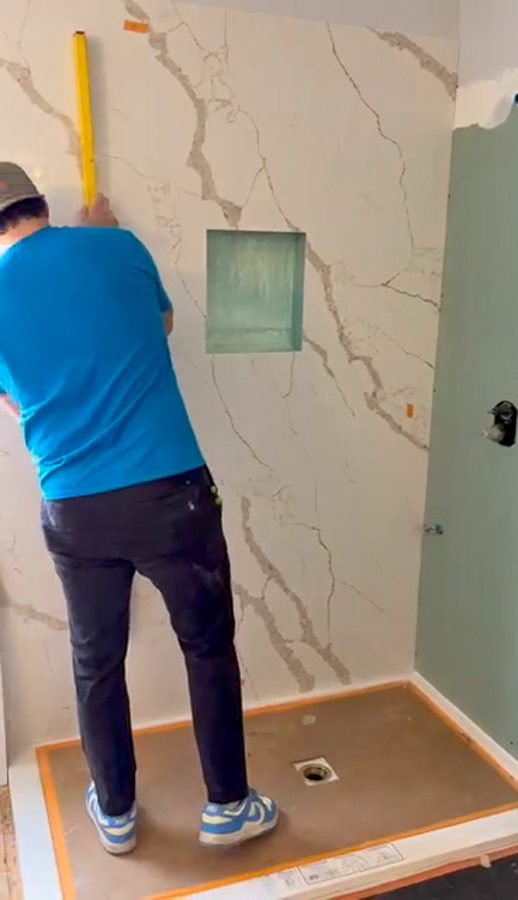An Orange Cactus Remodeling installer setting a marble-look shower panel during a bathroom remodel