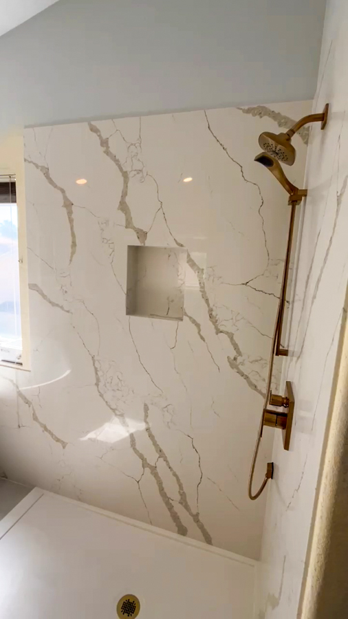 Walk-in shower with marble-look wall panels, a recessed niche, and a brushed-gold fixture, remodeled by Orange Cactus Remodeling, serving Ahwatukee, AZ