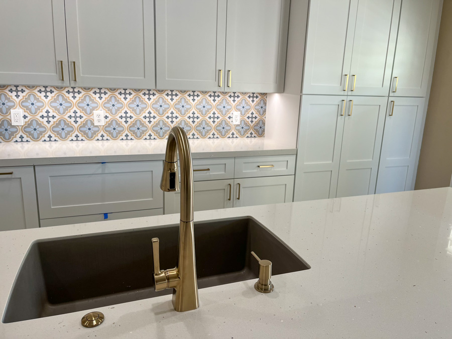 Kitchen sink detail with a brushed-gold faucet and a patterned tile backsplash from an Orange Cactus remodel