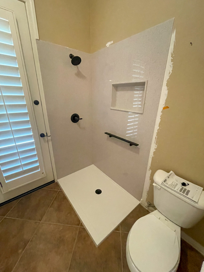 Low-threshold walk-in shower with a grab bar, a recessed niche, and matte-black fixtures, built by Orange Cactus Remodeling, serving Sun Lakes, AZ