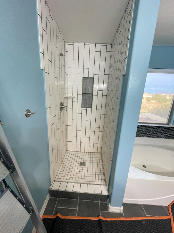 A narrow tiled shower with a step-over threshold beside a garden tub, the layout a Sun Lakes bathroom remodel usually replaces
