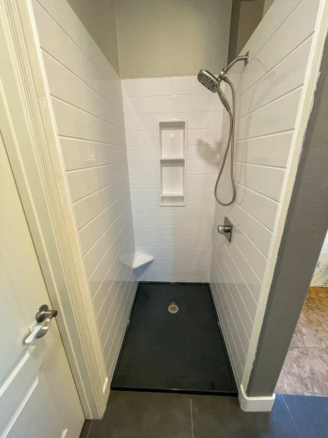 Walk-in shower with white shiplap walls and a low-maintenance panel system
