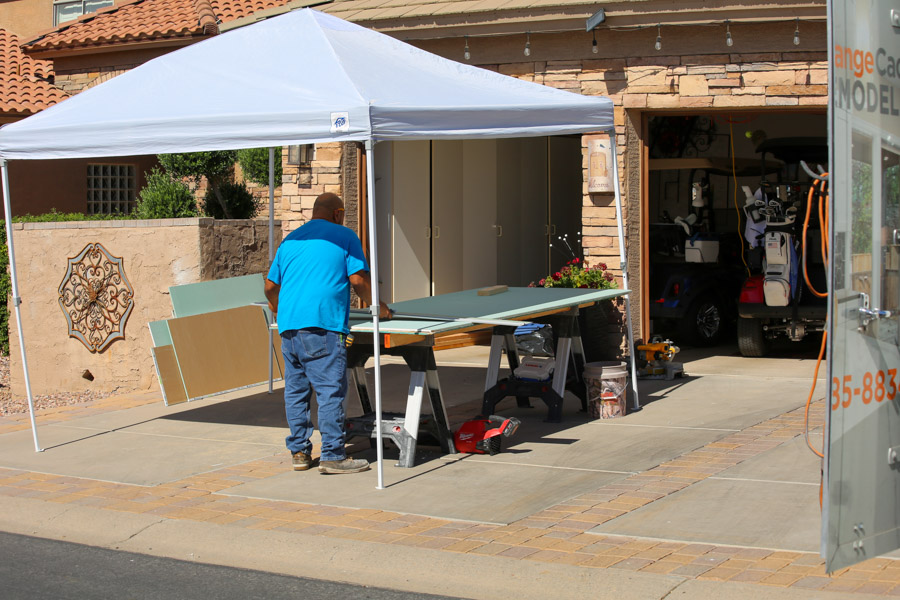 An Orange Cactus Remodeling crew member cutting material under a canopy in the driveway during a whole-home remodel, serving Ocotillo, Chandler, AZ