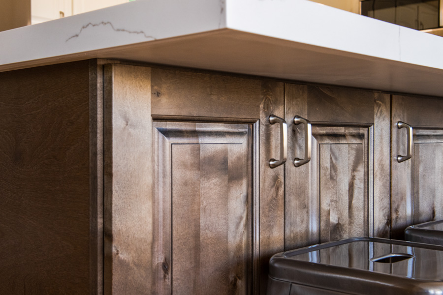 Builder-grade stained cabinetry under a quartz countertop, the finish level most first remodels replace